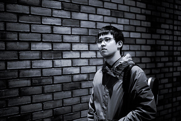 Violinist Yuwen Fan in black and white against a brick wall