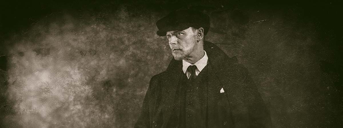 Peaky Blinders 1200x450 - Black and white photo of a man in a peaky cap