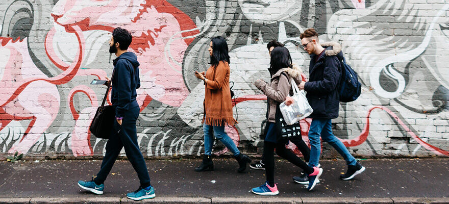 A group of students walking past colourful street art in Digbeth 