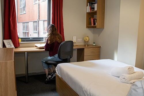 A student works at a desk in one of the University Locks bedrooms