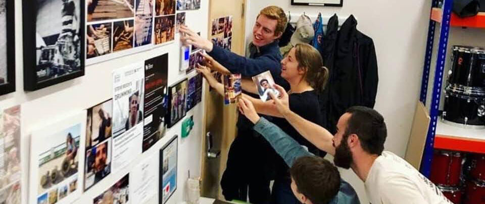 Adding to the photo collection in the percussion store - four people looking at photos on a wall