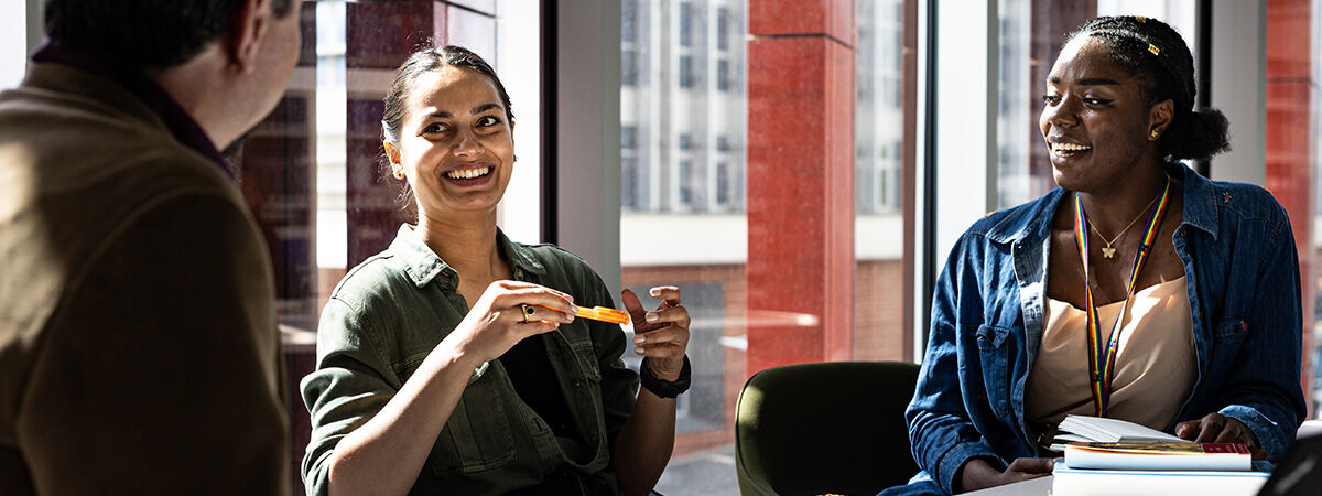 Black woman laughs whilst studying in a red room