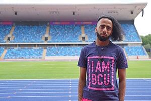 A BCU sports student stands on the running track in the Alexander Stadium