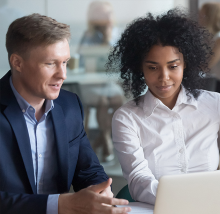 Professional man and woman sat next to each other looking at laptop