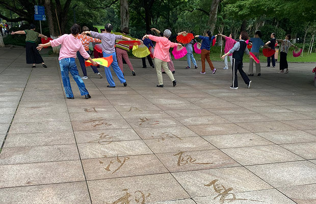 People holding flags in a park with Chinese writing on the floor