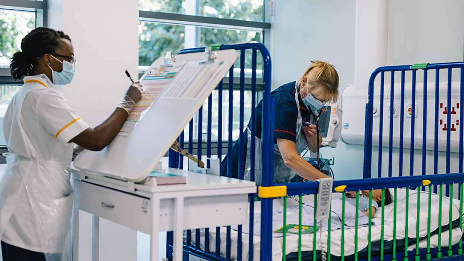 Nursing students monitoring a baby in a mock ward