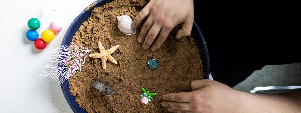 Child adding shapes to sand
