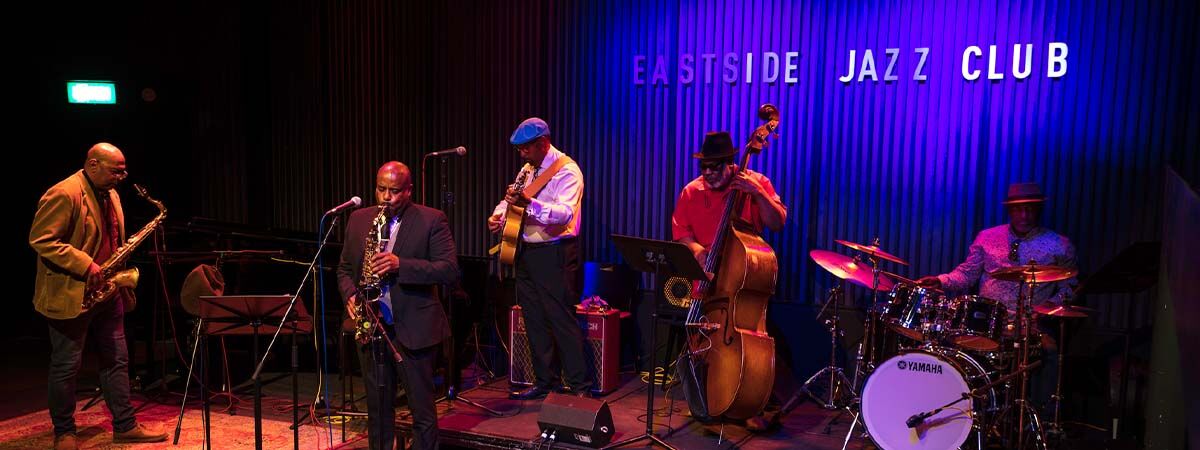 A group of musicians playing jazz in Eastside Jazz Club, the lighting is dark and atmospheric 