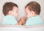 Twin babies sleeping face to face under a blanket