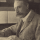 Black and white image of Edward Elgar, English composer, sat at a desk