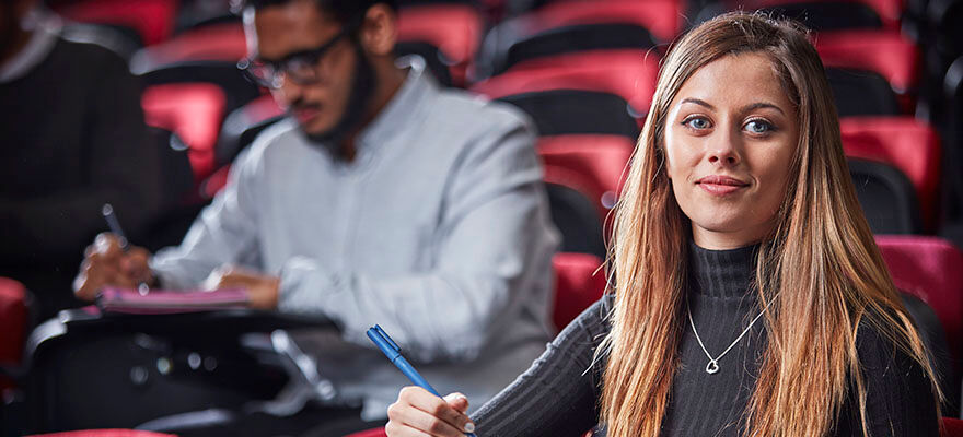 EVE CRM Top Image 880x400 - Woman sat in a lecture theatre, looking at the camera