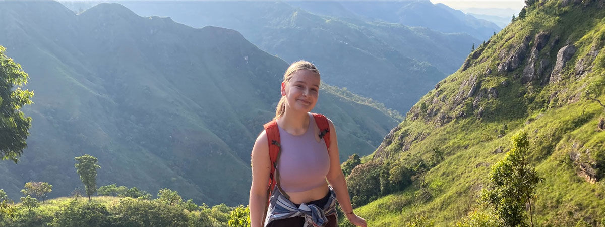 student on hiking trail with mountains in the background