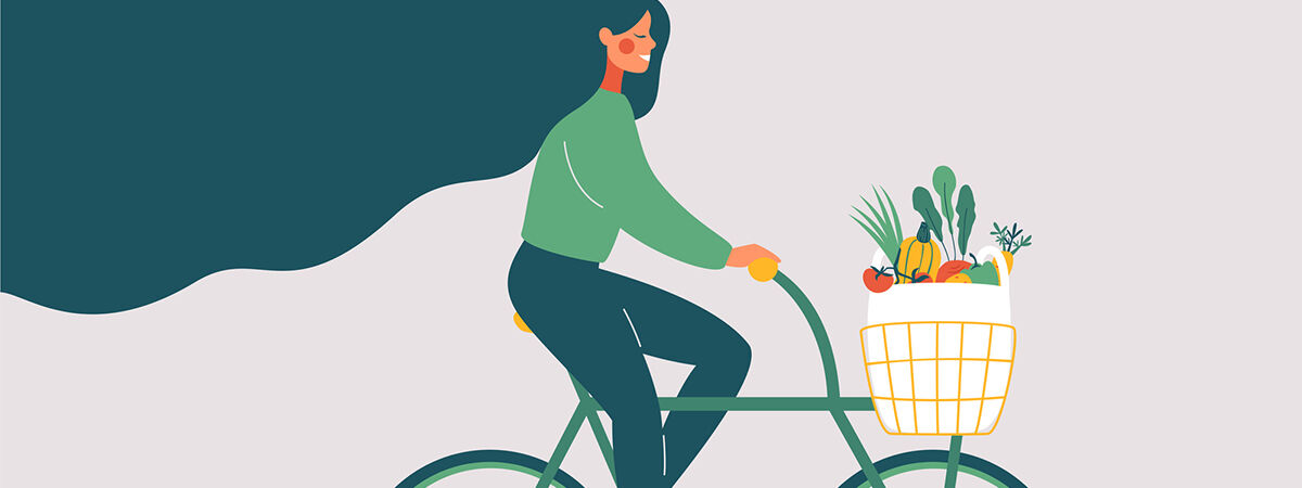 A woman rides a bicycle filled with sustainable produce, just one of the ways people can go green