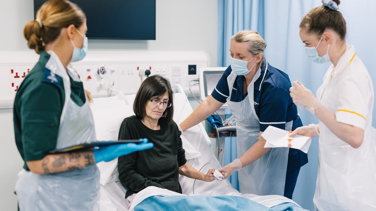 Health profession students tend to a patient in bed