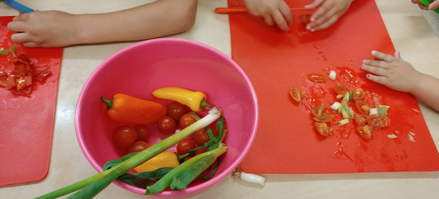 Young children cutting up vegetables 