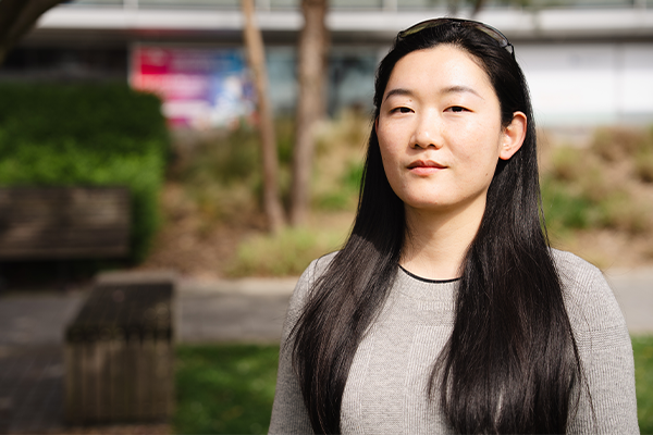 An asian woman looks forward proudly in a green space