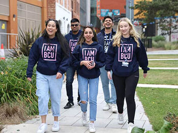 Group of students wearing I am BCU hoodies, walking at City Centre campus