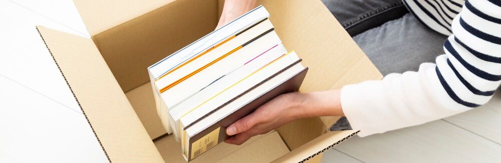 Person placing books into a shipping box