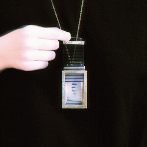 A student wearing a necklace with a silver mirror attached to the chain