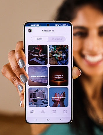 Dalbir Kaur proudly holding the Makemefitclub health and wellbeing app.