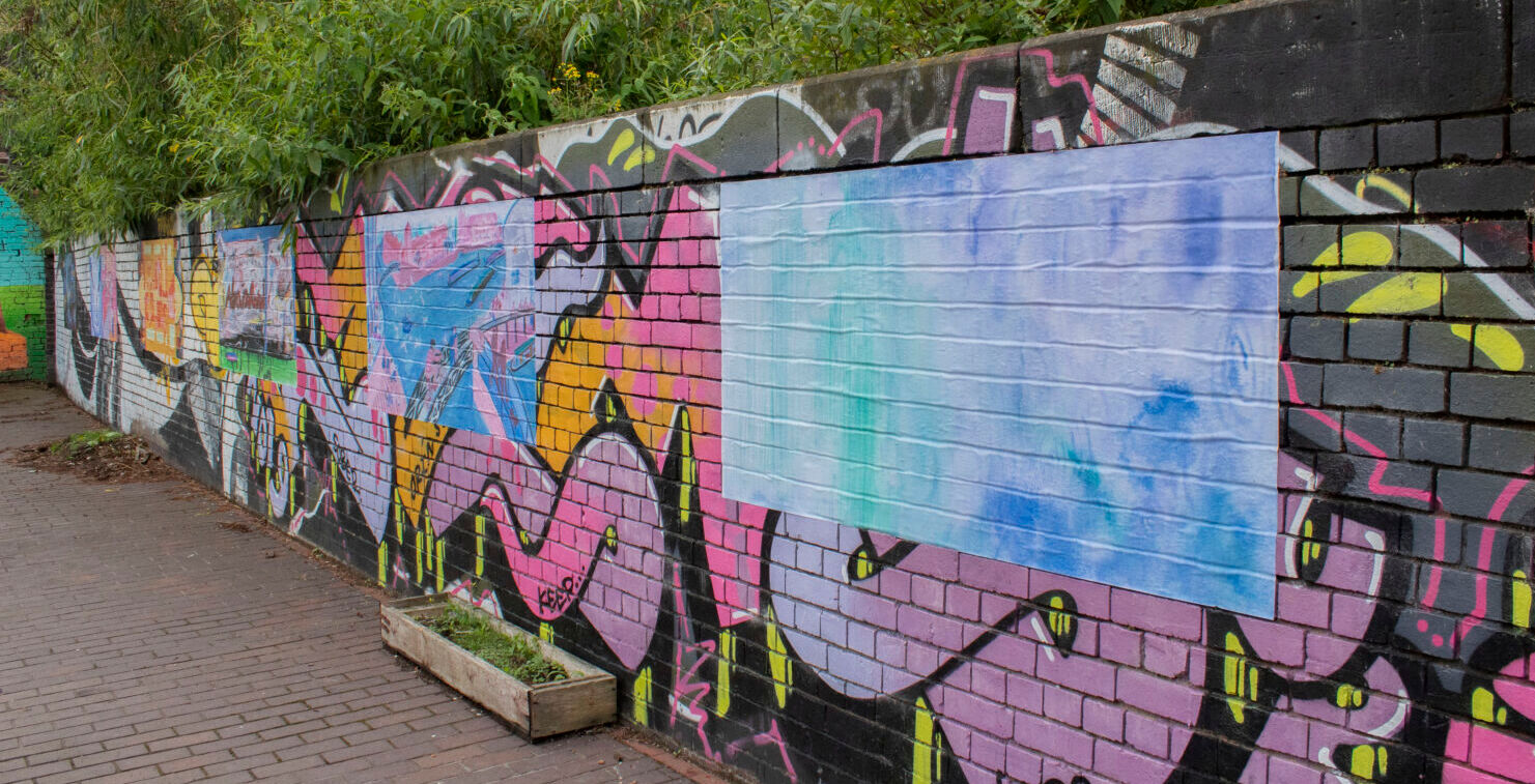 Image of colourful canalside artwork with foliage above