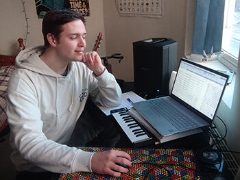 Nat Evans, RBC student arranging music using keyboard and computer software