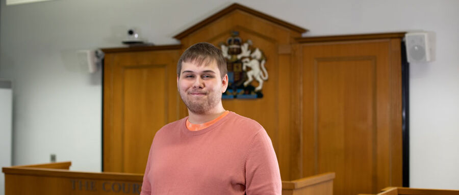 Nathan stands in BCU's mock law courts and looks confidently into the camera