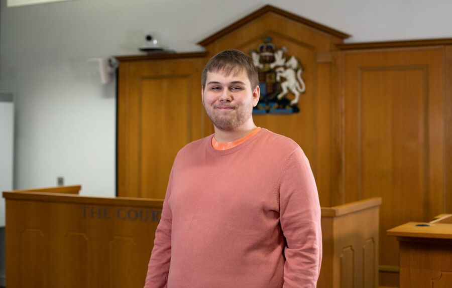 Nathan stands in BCU's mock law courts and looks confidently into the camera