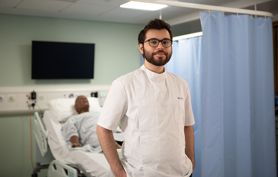 Nicholas stands in front of a hospital bed in one of our mock hospital wards