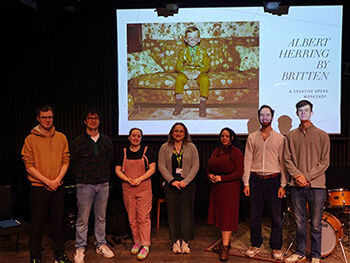 Sixth form students at RBC opera in front of banner for Albert Herring by Britten