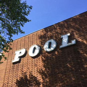 A brown building with a patterned brickwork. In white letters it says 'Pool'. Photo credit: Tom Hicks