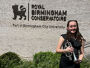 Poppy Taylor holding percussion instrument outside Royal Birmingham Conservatoire building