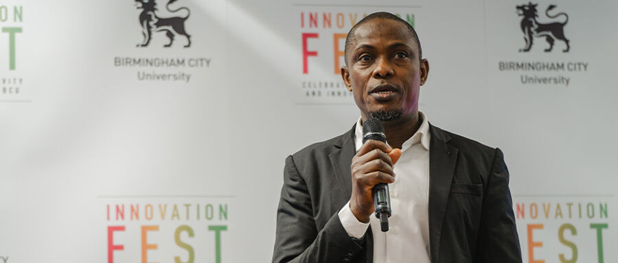 PhD Student Rasheed Ayoola giving a speech with Innovation Festival banners in the background