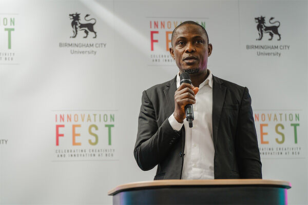 PhD Student Rasheed Ayoola giving a speech with Innovation Festival banners in the background