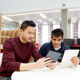 Two students looking at a tablet in the library