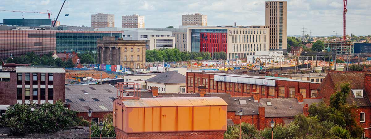 An aerial view of Birmingham city centre and Digbeth, featuring a mix of old and modern buildings, with construction cranes visible in the background.