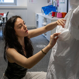 Student dressing a mannequin with wedding style gown