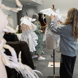 Student styling white garment on mannequin in workshop