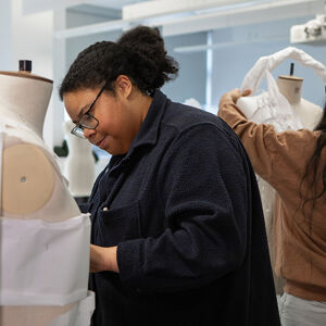 Two students working on mannequins with twisted white fabric