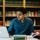 A BCU academic working on a laptop in a library