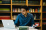 A BCU academic working on a laptop in a library