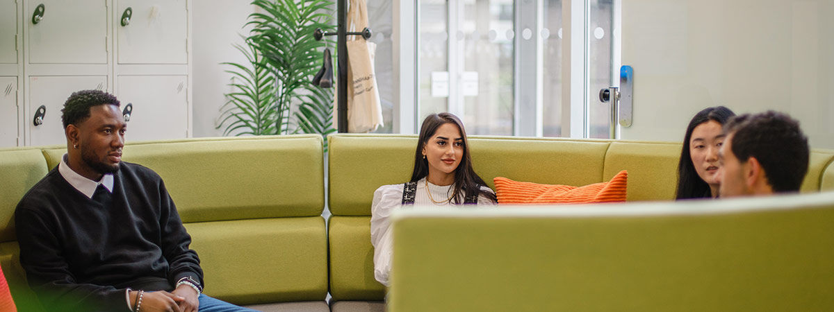 Four students sat on round sofa talking