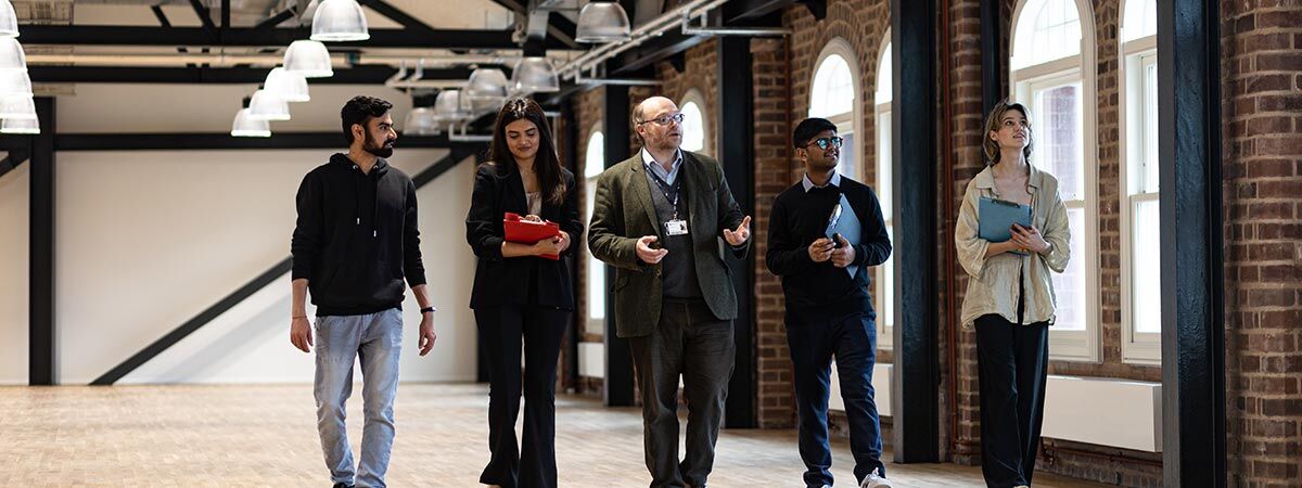 Five people walking through a building looking around, three of them with clipboards