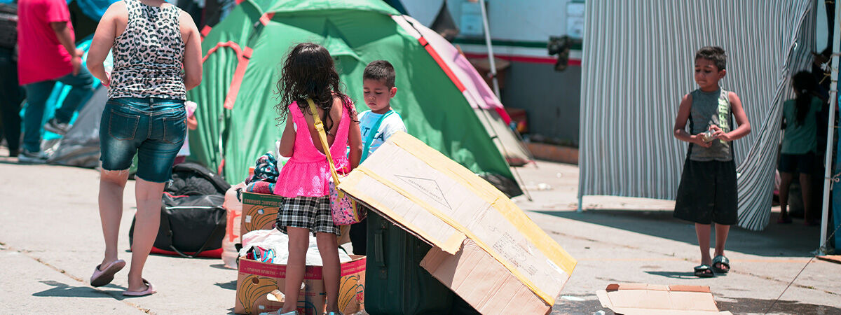 Refugee children standing with one another amongst tents