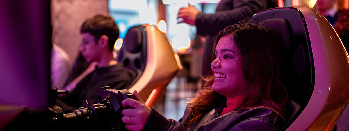 Students playing an F1 simulation game in an arcade bar