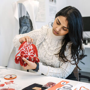 student holding up red textile design