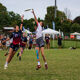 Two people are play Ultimate Frisbee in a competitive game on a field. They are both jumping to try and catch the frisbee