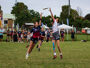 Two people are play Ultimate Frisbee in a competitive game on a field. They are both jumping to try and catch the frisbee