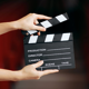 A person holding a clapper board above a red seat, ready to start filming.