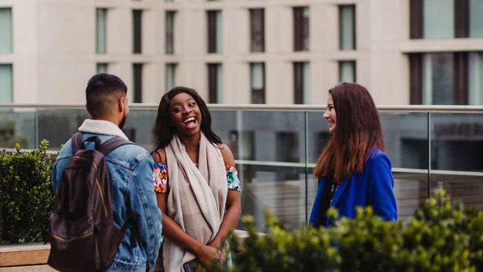 three students talk and laugh outside